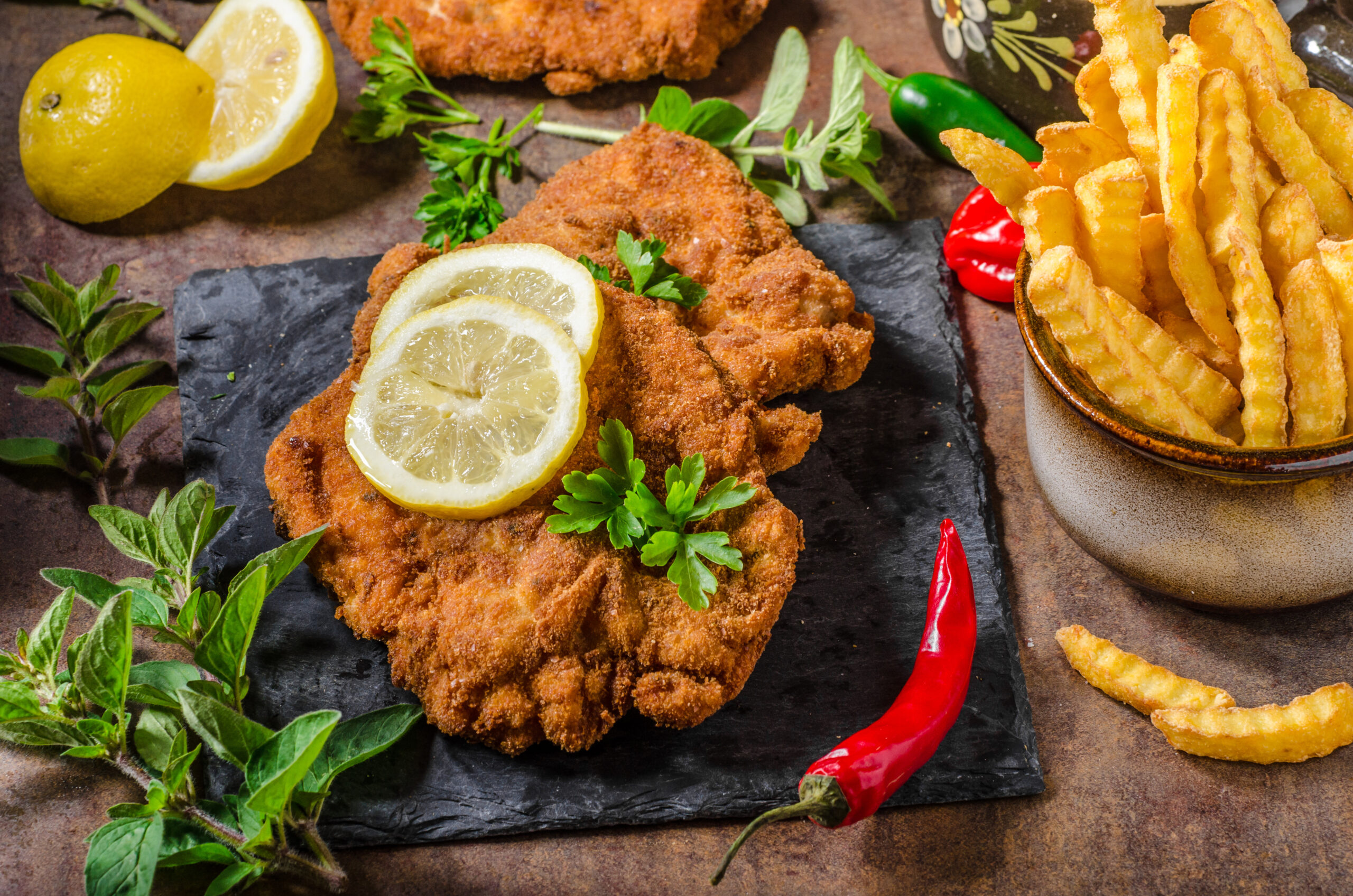 Schnitzel with fries, salad and herbs, hot chilli tomato sauce