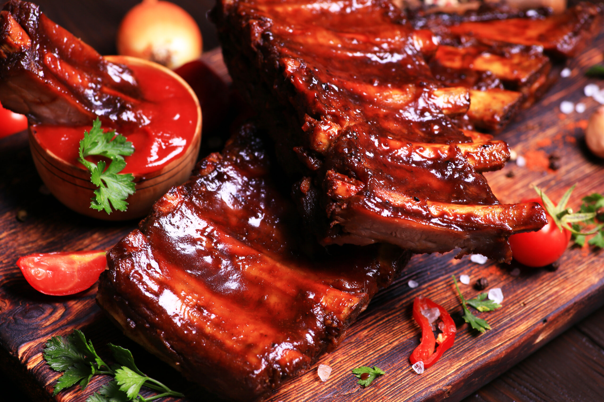 Grilled pork ribs with spices and vegetables on a wooden background